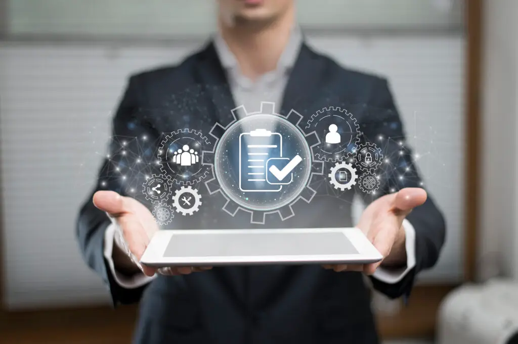 Businessman holding a digital tablet with floating holographic icons representing enterprise resource planning (ERP), automation, workflow management, and service operations.